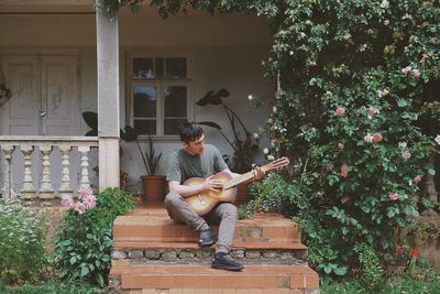 Full length of young man playing guitar at porch