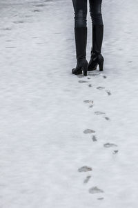 Low section of woman walking on snow covered field