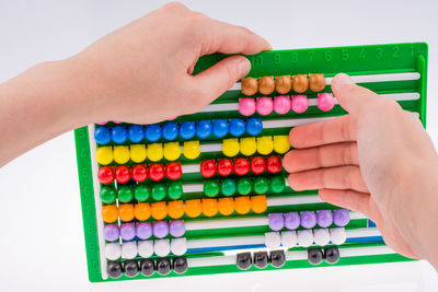 Close-up of hand holding abacus over white background