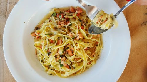 Directly above shot of tagliatelles with spoon and fork served on table