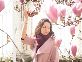 Thoughtful woman standing by pink flowers 