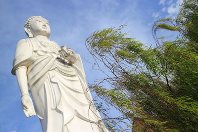 Low angle view of buddha statue against sky