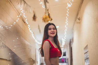 Portrait of beautiful woman standing in illuminated room