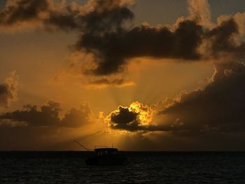 Silhouette boat in sea against sky during sunset