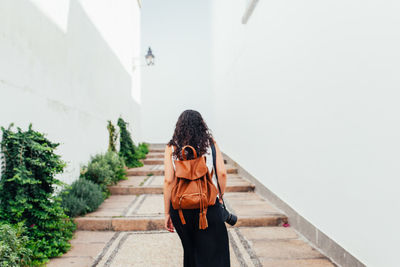 Rear view of woman walking on walkway against clear sky