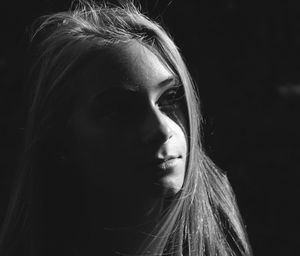 Close-up portrait of young woman over black background