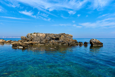 Rock formations by sea against blue sky