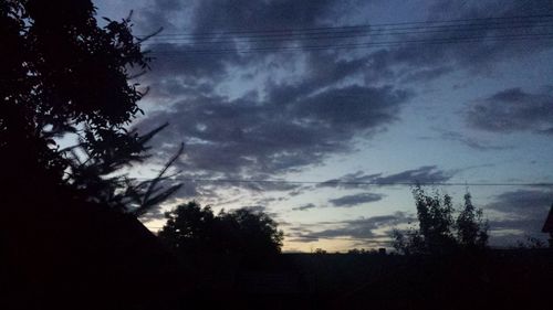 Silhouette trees on landscape against scenic sky