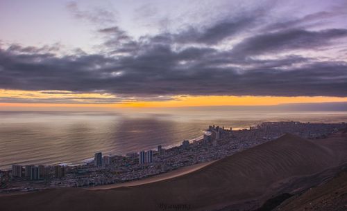 Scenic view of sea and buildings against sky during sunset