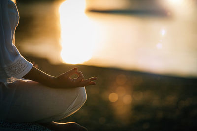 Sungazing. woman meditating by the lake, sitting in lotus position.