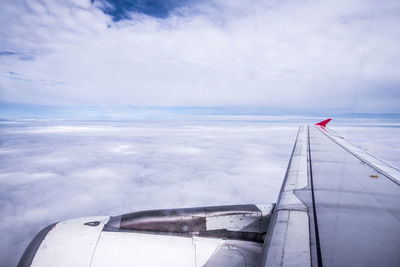 Close-up of airplane wing against cloudy sky