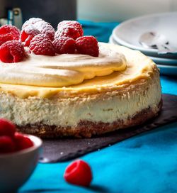 Cheesecake garnished with raspberries on table