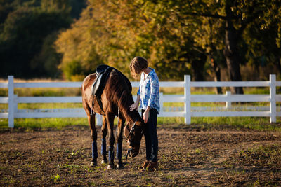 Woman standing with horse in ranch