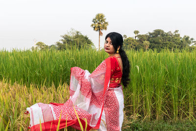 Portrait of young woman standing on field