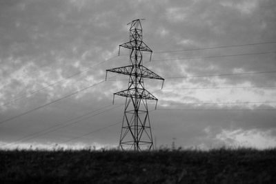 Low angle view of electricity pylon on field