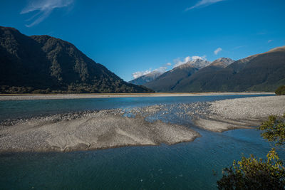 Scenic view of lake and mountains against blue sky