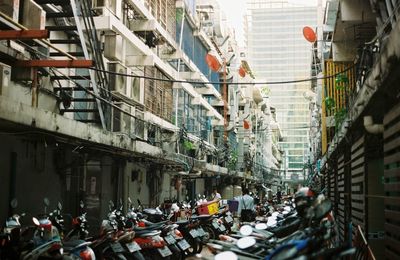 Motorcycles parked in alley amongst buildings in city