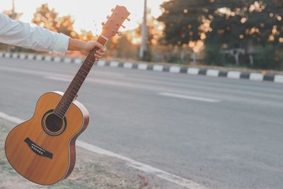 Hand holding a guitar separately sunset