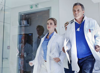 Female and male doctors running in corridor during urgency in hospital