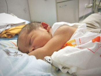 Close-up of baby sleeping on bed at home