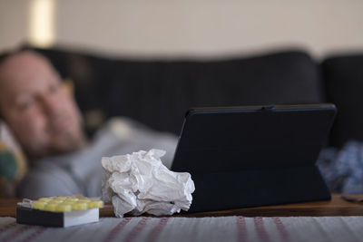 Sick man lying at home and using digital tablet