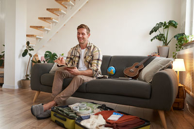 Portrait of woman using phone while sitting on sofa at home