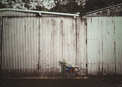 Empty bench by fence against wall