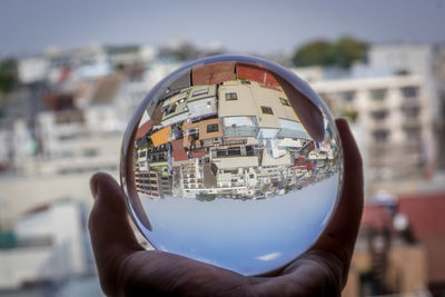 Close-up of hand holding sunglasses against cityscape