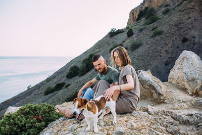 Happy couple with favourite pet. young man and woman have walk near sea.