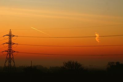 Low angle view of silhouette electricity pylon against sky during sunset