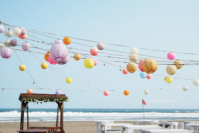 Low angle view of lanterns hanging by sea against clear sky