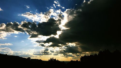 Silhouette of trees against cloudy sky