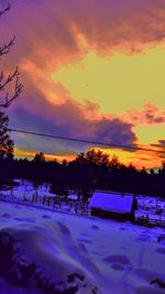 Silhouette trees on snow covered landscape against sunset sky