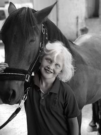 Portrait of smiling girl stroking horse
