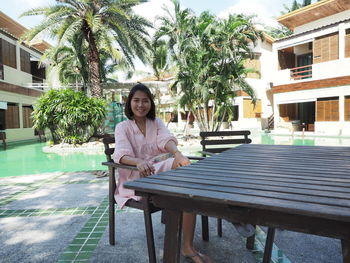 Portrait of young woman sitting in swimming pool against building