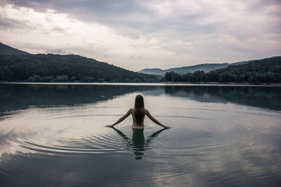 Rear view of man in lake against sky