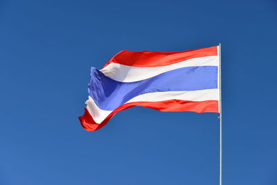 Low angle view of flag against blue sky