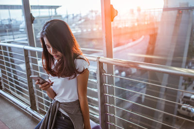 Woman using smart phone while sitting at airport