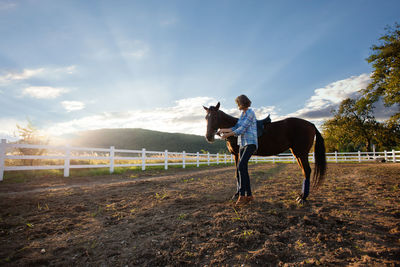 Full length of woman standing with horse against sky