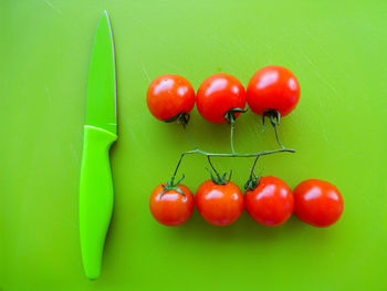 High angle view of cherry tomatoes with knife on green table