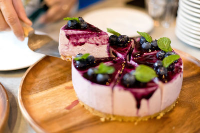 Cropped hand serving cake at table