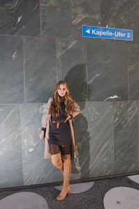 Portrait of woman standing against wall