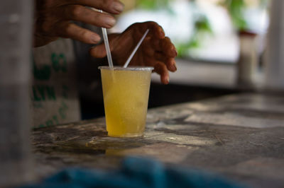 Close-up of hand holding glass of drink on table