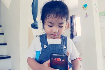 Cute baby girl playing phone cover at home