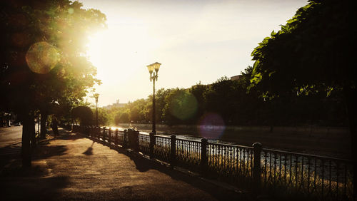 Street by river against sky during sunset