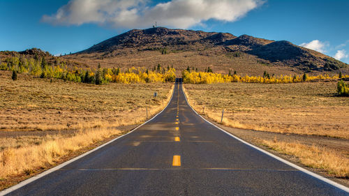 Road leading towards mountain against sky