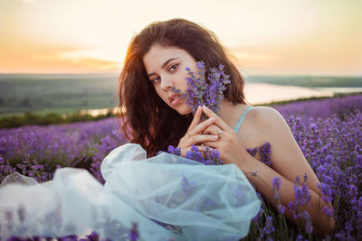 A beautiful young girl against the sunset and a beautiful sky in a lavender field. 