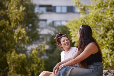 Smiling young women sitting outdoor and talking to each other