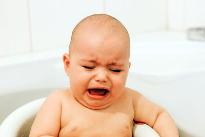 Portrait of shirtless baby boy in bathroom