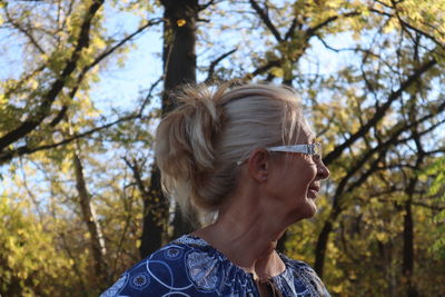 Close-up of thoughtful senior woman wearing eyeglasses while standing against trees